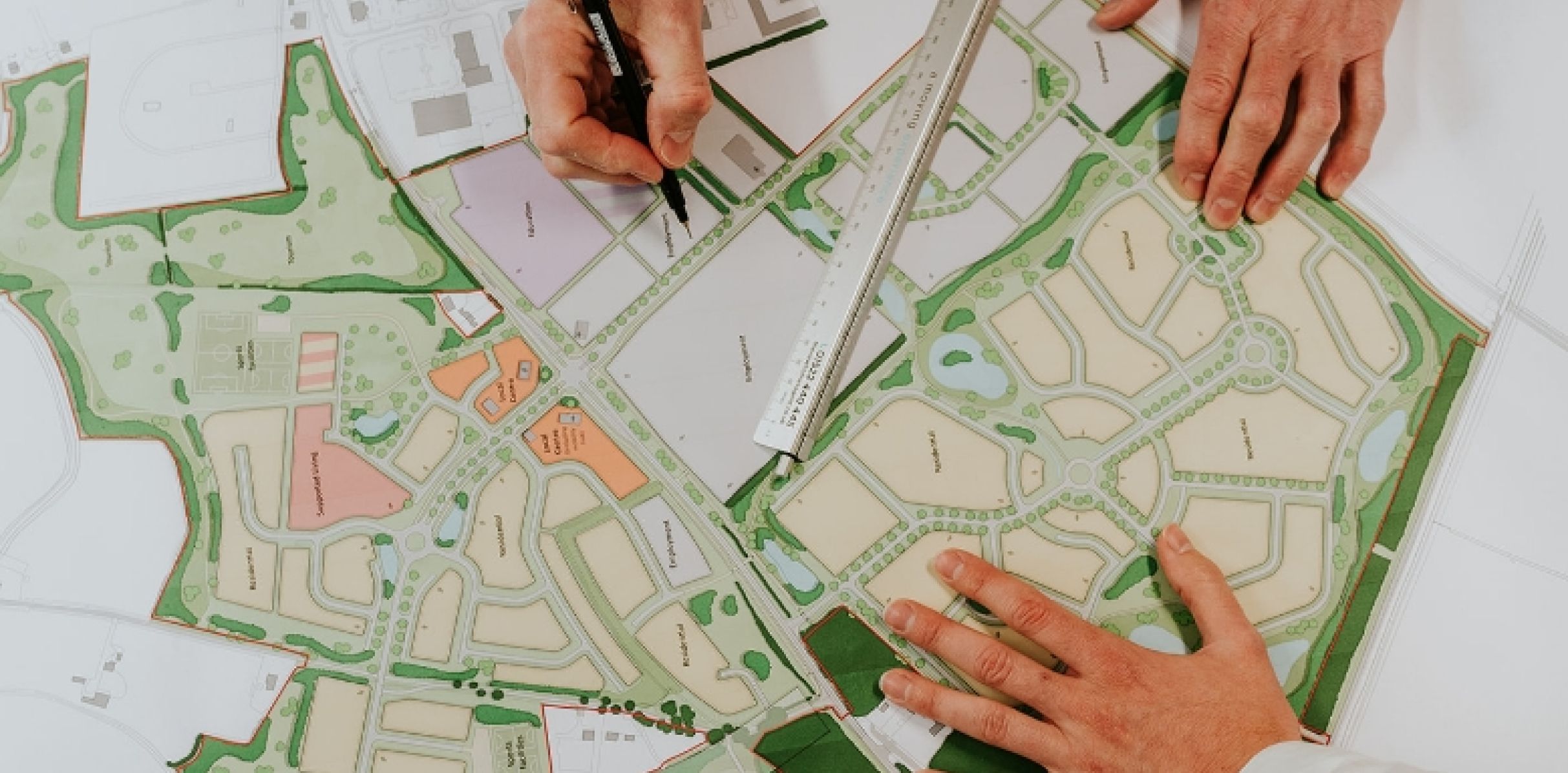 Hands making notes on a land plan