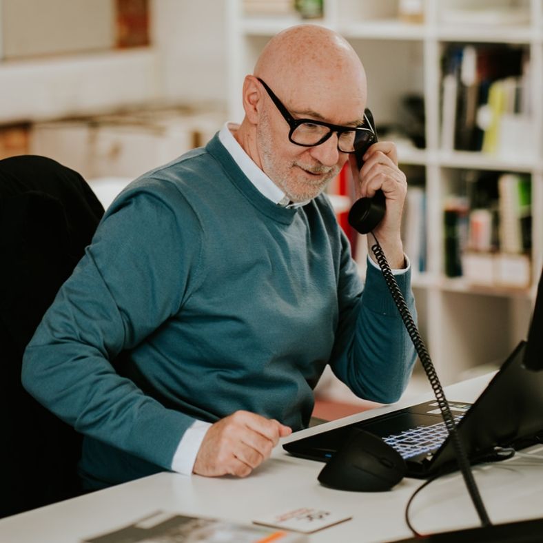A man on the phone looking at a laptop screen