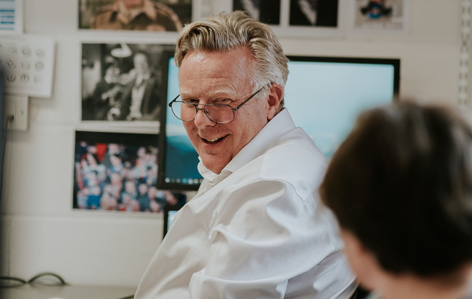 A man turning around smiling at another person